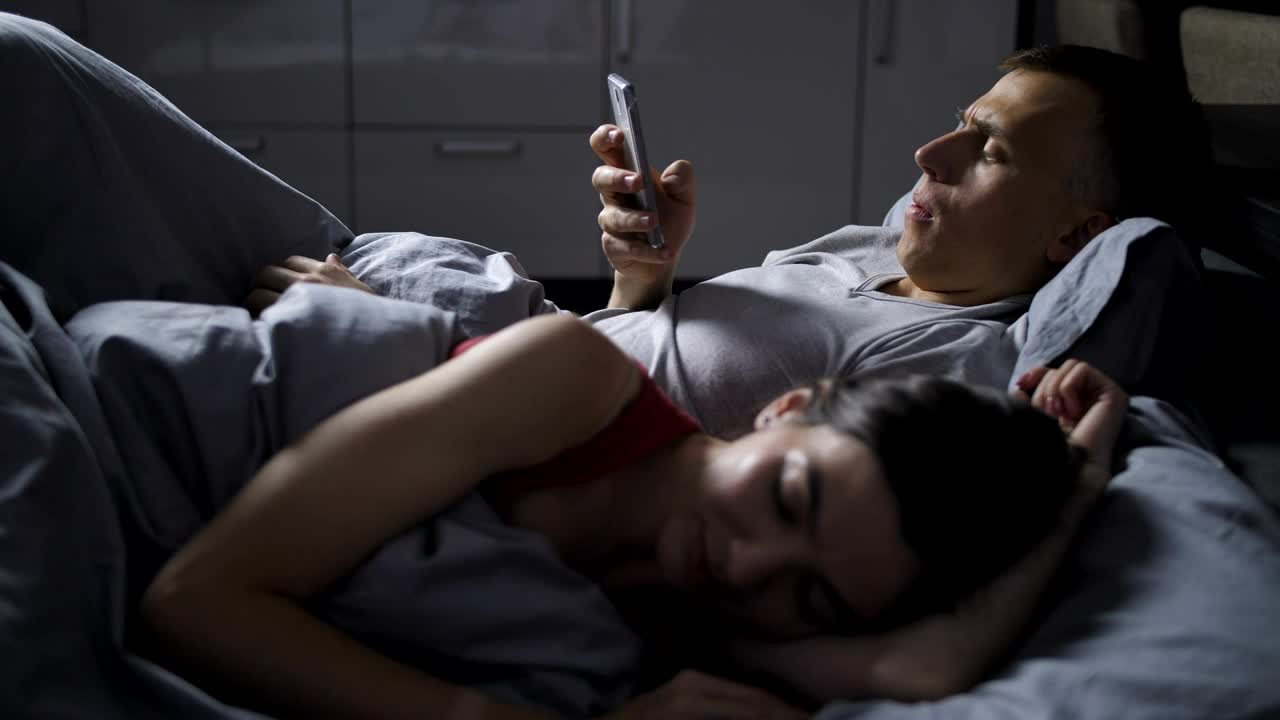 Stock Video Man Using His Phone While His Wife Sleep Animated Wallpaper - Free Download
