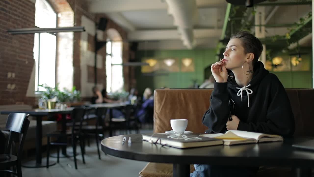 Stock Video Hip Woman Thinking In Cafe Writes Down Idea Animated Wallpaper - Free Download