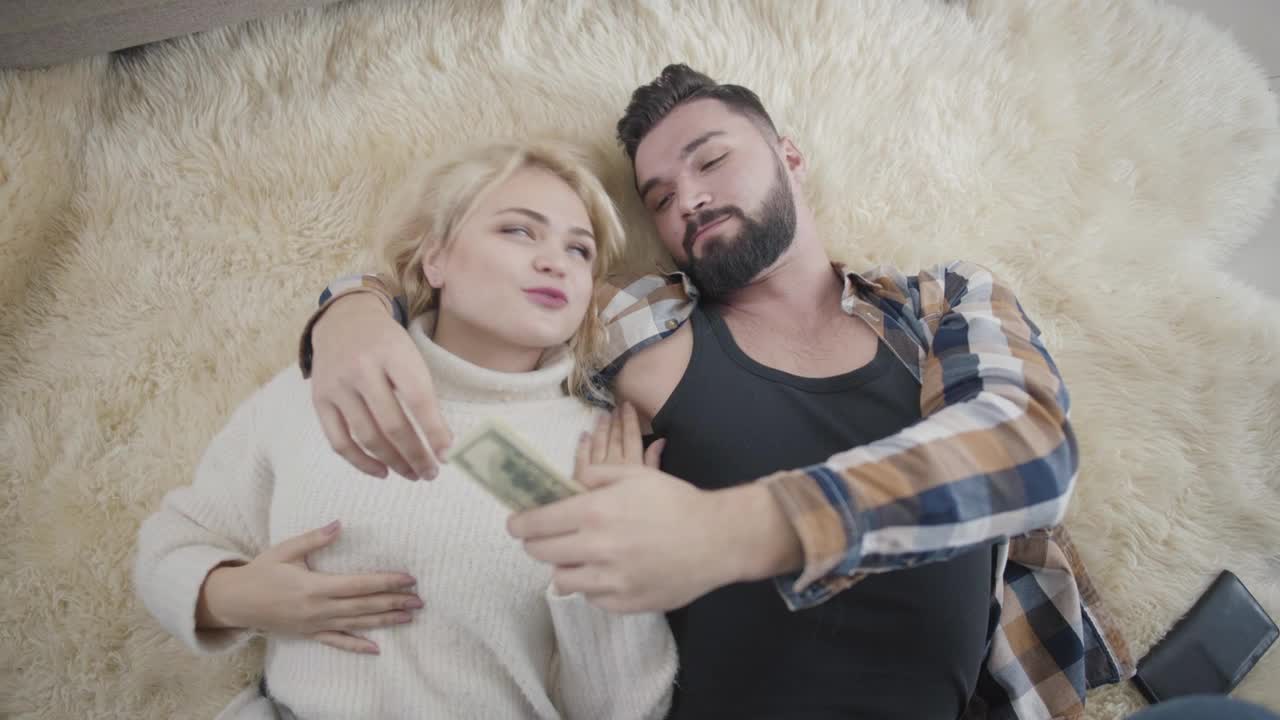 Stock Video Happy Rich Couple Lay On Rug And Count Cash Animated Wallpaper - Free Download