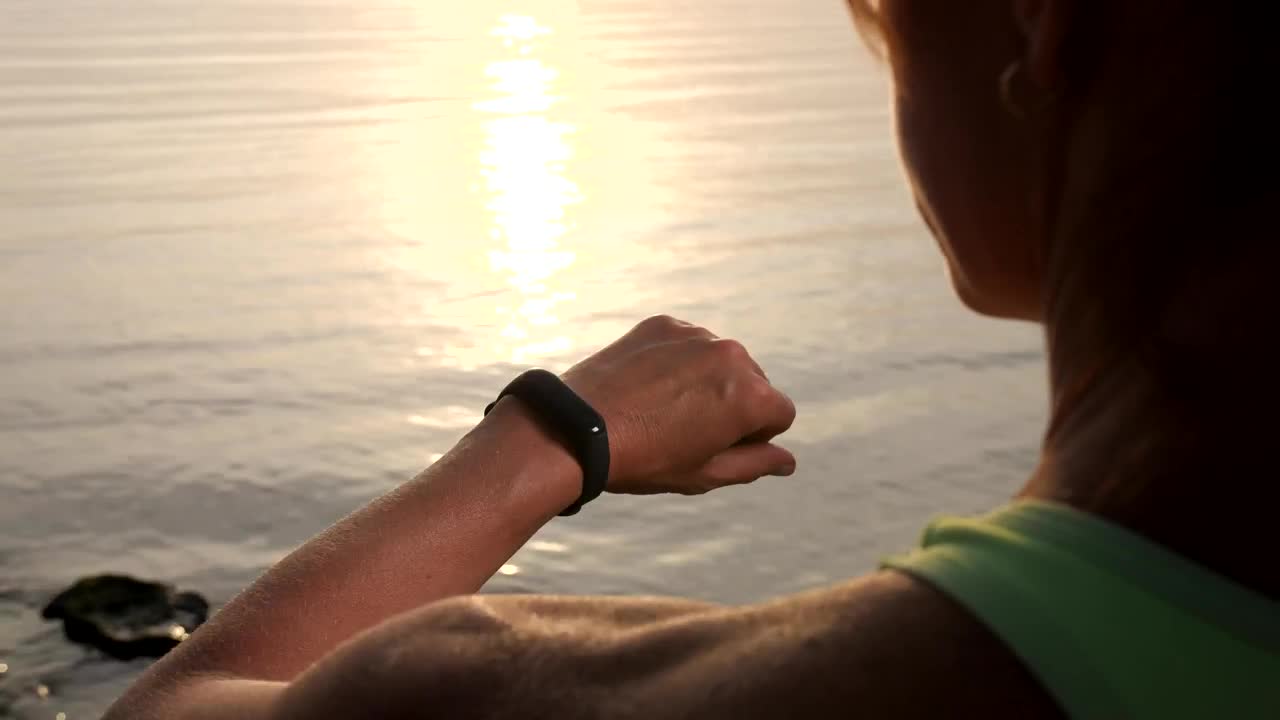 Free Stock Video Woman Checks Her Smart Watch While Watching Sunset Live Wallpaper - Free Download