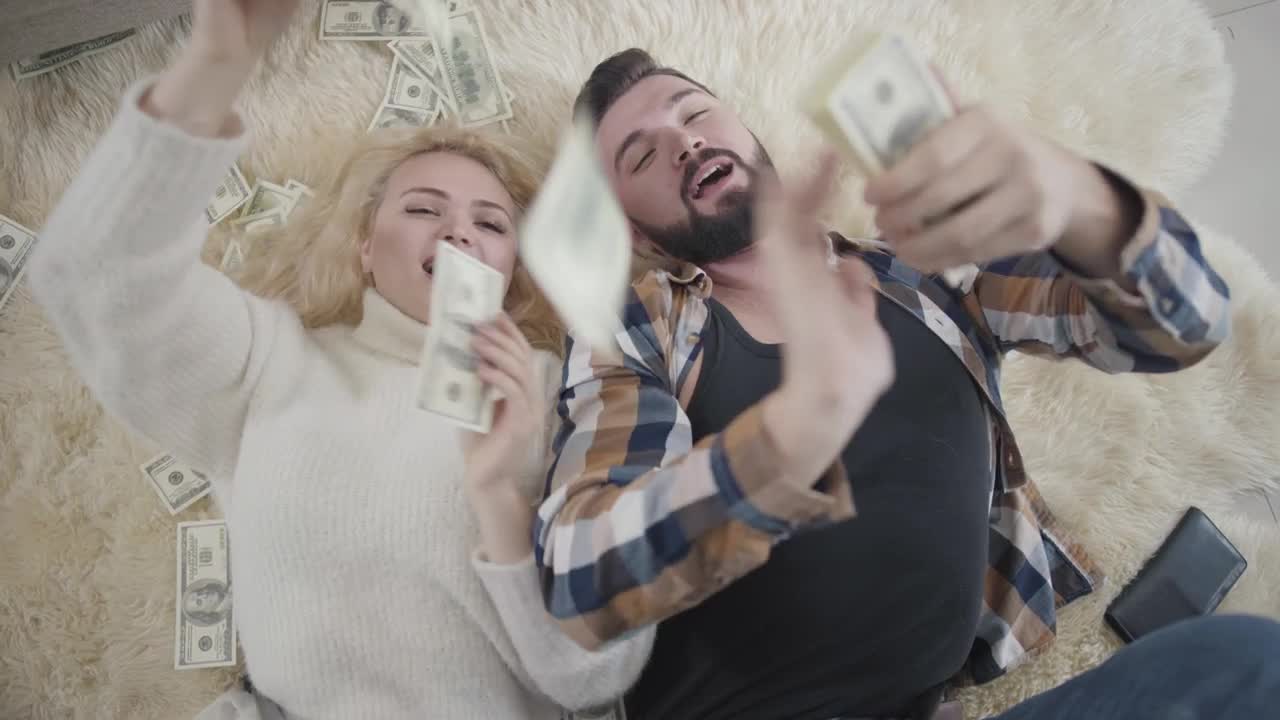 Free Video Stock top view of rich couple on rug laying in money Live Wallpaper - Free Download