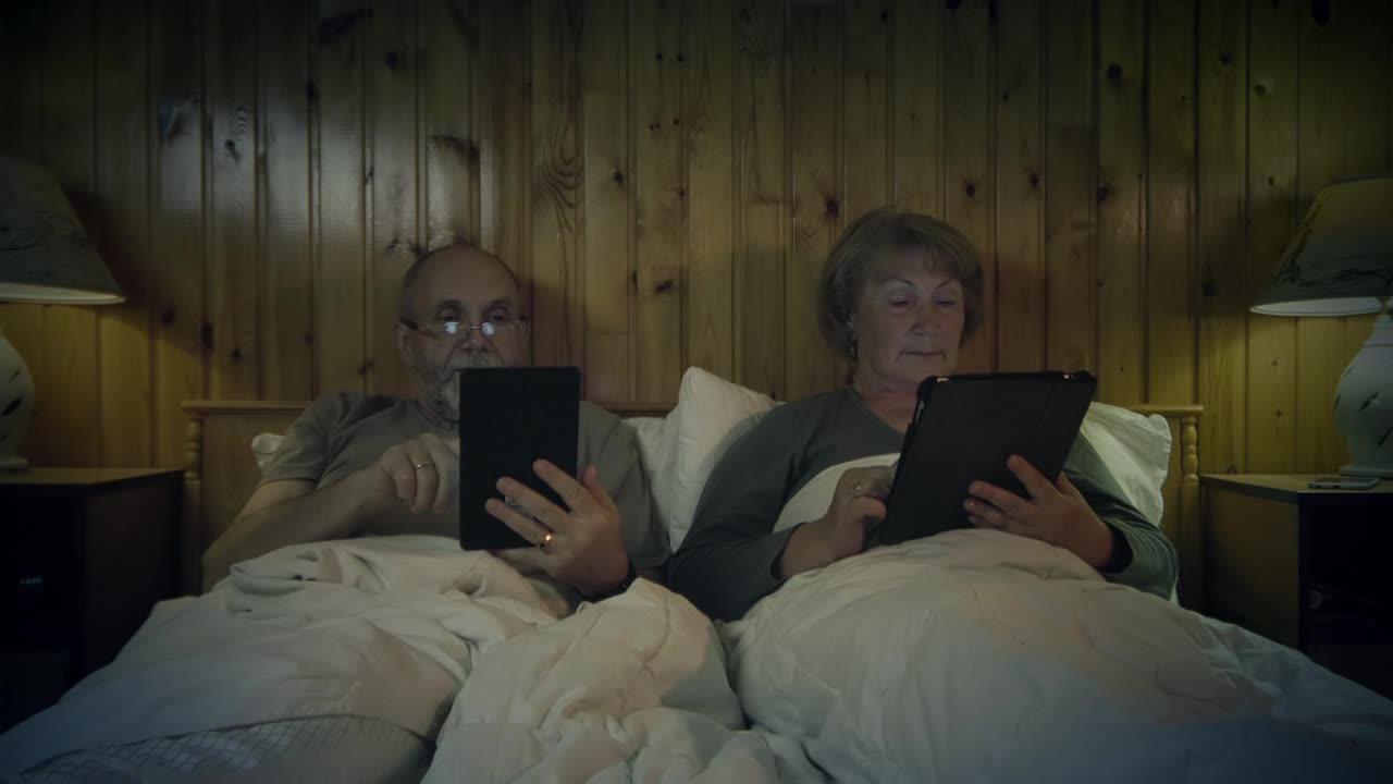 Free Stock Video Senior Couple Reading On The Bed With Devices Live Wallpaper - Free Download