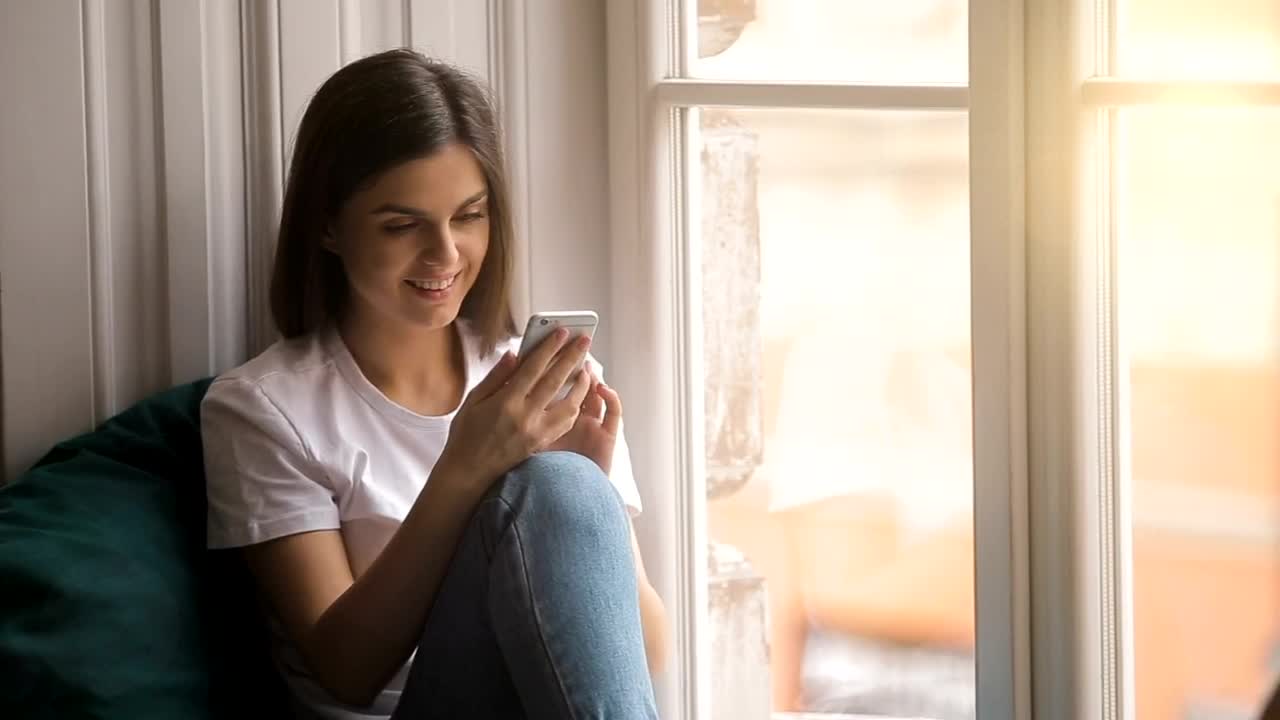 Stock Video Happy Woman Uses Mobile App Sitting In Window Animated Wallpaper - Free Download