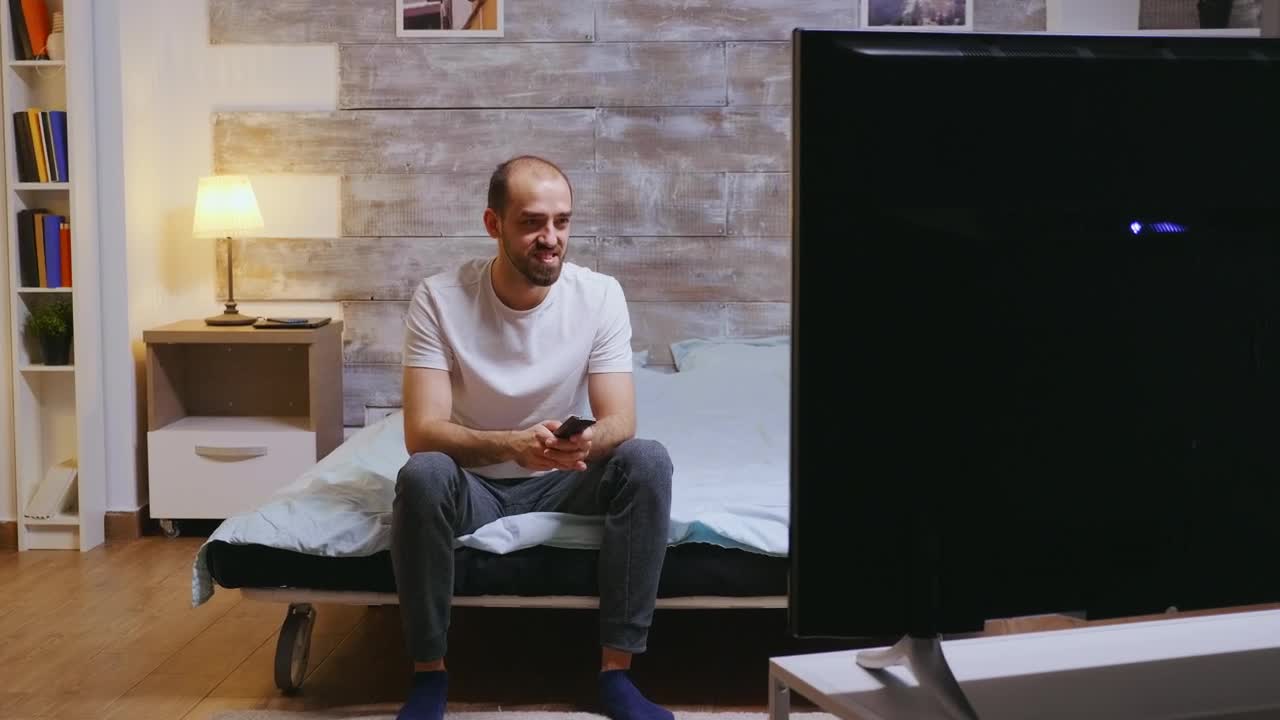 Stock Video Man Sits On Bed Laughing At Comedy On T Animated Wallpaper - Free Download