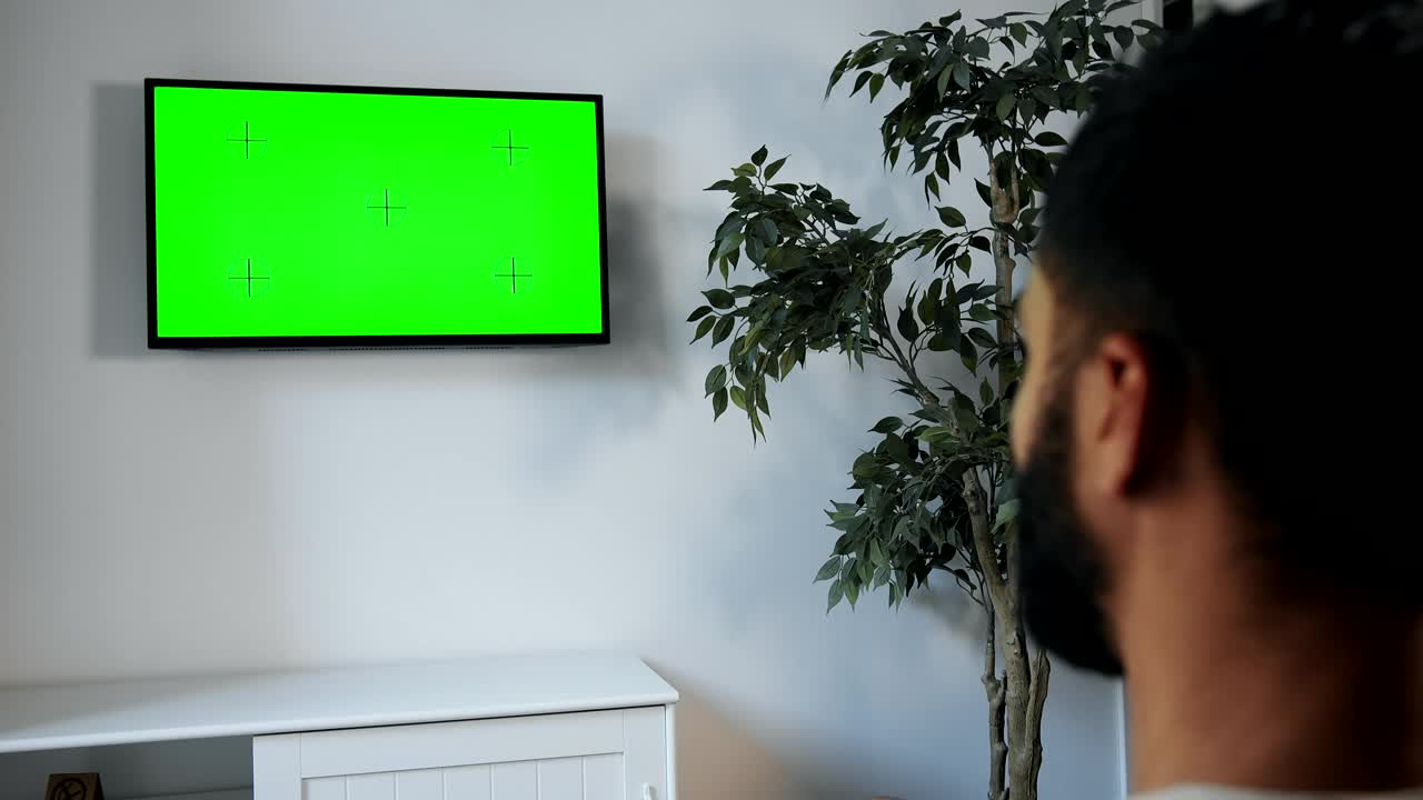 Stock Video Man Points Remote At Green Screen Tv On Wal Animated Wallpaper - Free Download