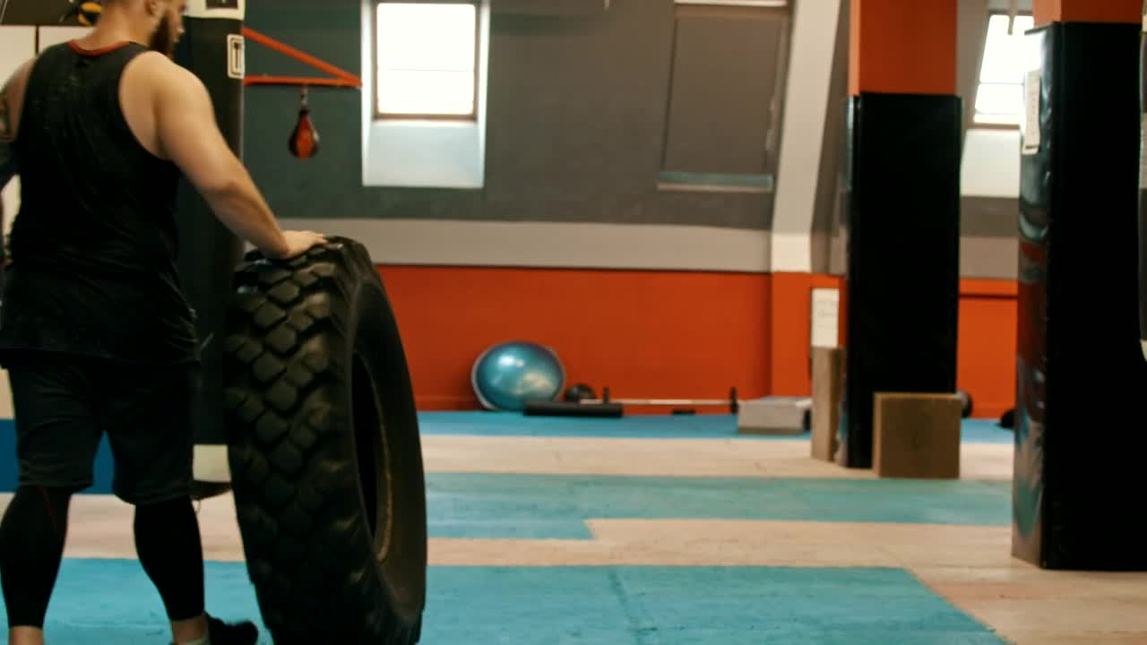 Stock Video Man In A Gym Walking With A Big Truck Wheel Animated Wallpaper - Free Download