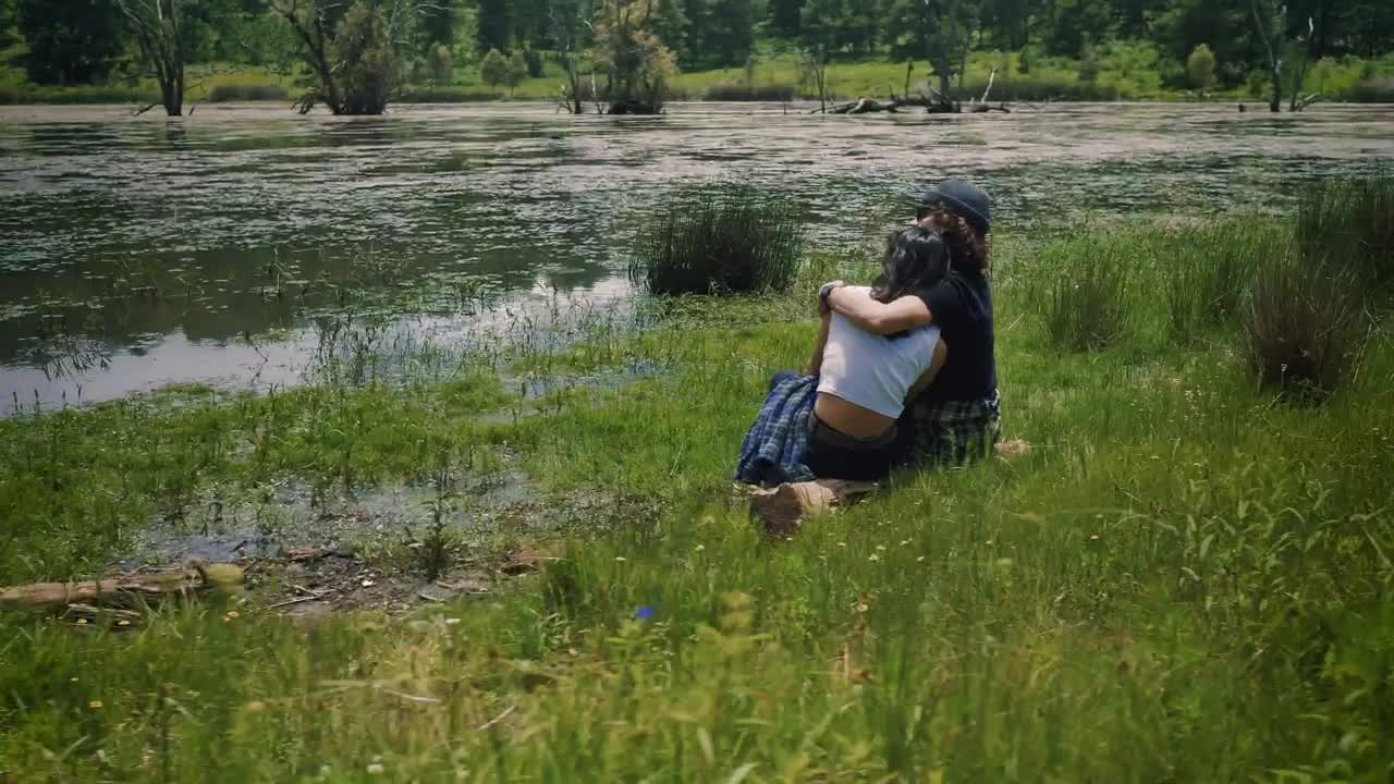 Stock Video Loving Couple Sitting On The Shore Of A Lake Outdoors Animated Wallpaper - Free Download