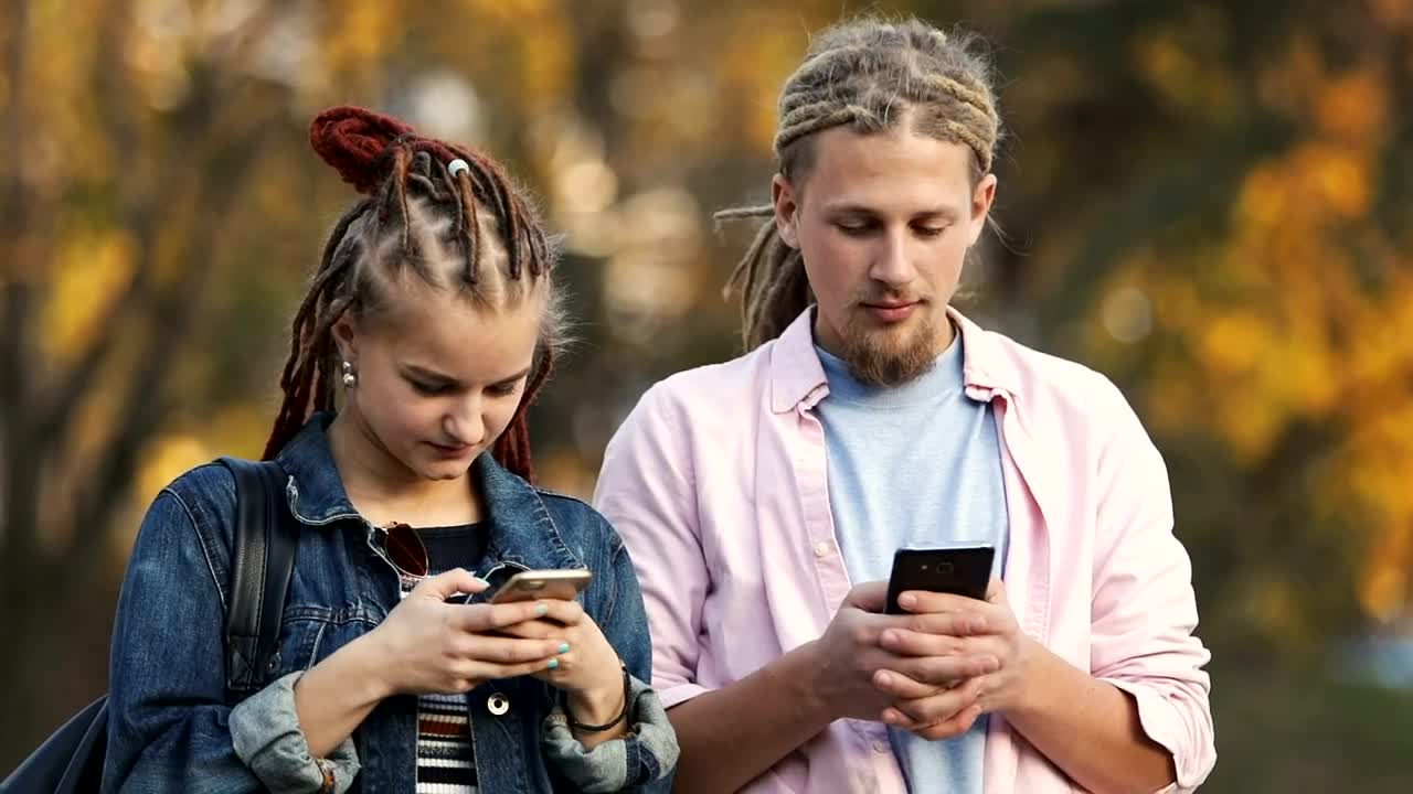 Stock Video Hip Urban Couple Surf Internet On Mobile Phones Outside In Animated Wallpaper - Free Download