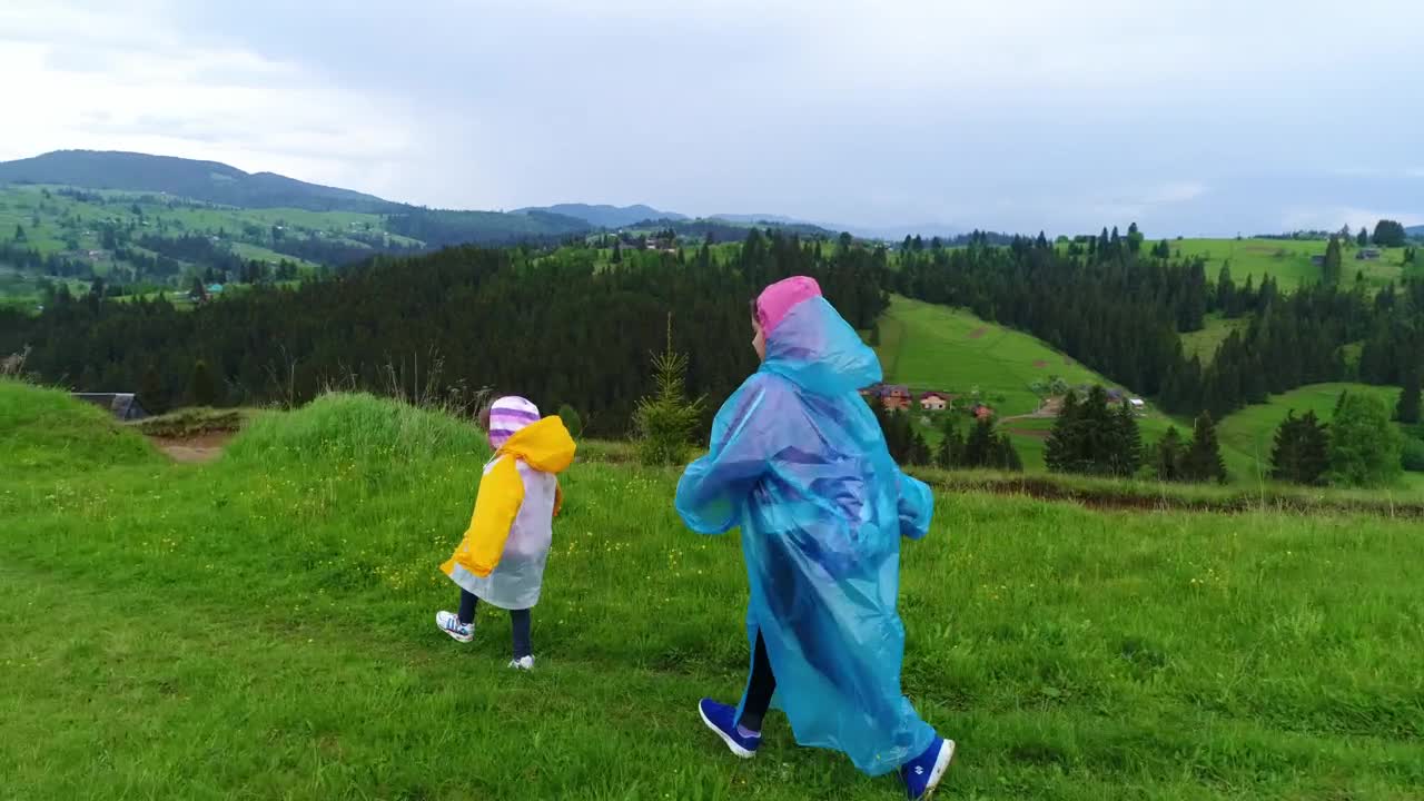 Stock Video Happy Sisters Walking Through The Field Wearing Raincoats Animated Wallpaper - Free Download