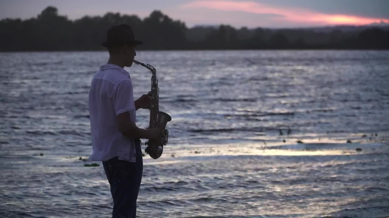Stock Video Man Plays Saxophone To Ducks By Lake At Sunse Animated Wallpaper - Free Download