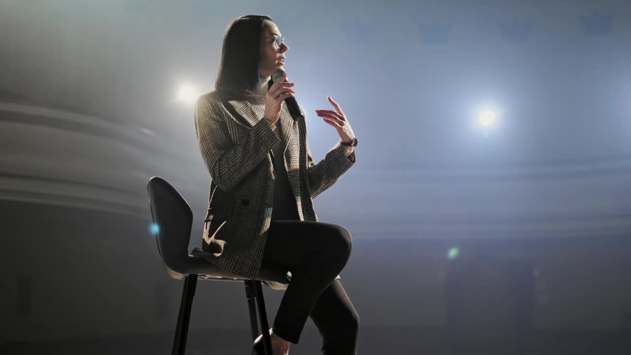 Stock Video Female Speaker Speaks To Audience Sitting On A Chair Live Wallpaper For PC - Free Download