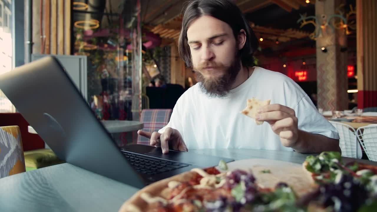 Stock Video Man Eats Pizza While Woking On Laptop At Hip Cafe Animated Wallpaper - Free Download