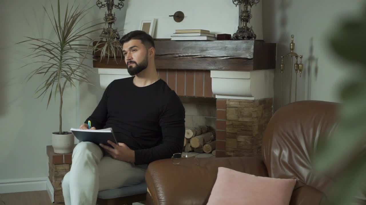 Stock Video Man Sits In Living Room Thinking And Writin Animated Wallpaper - Free Download