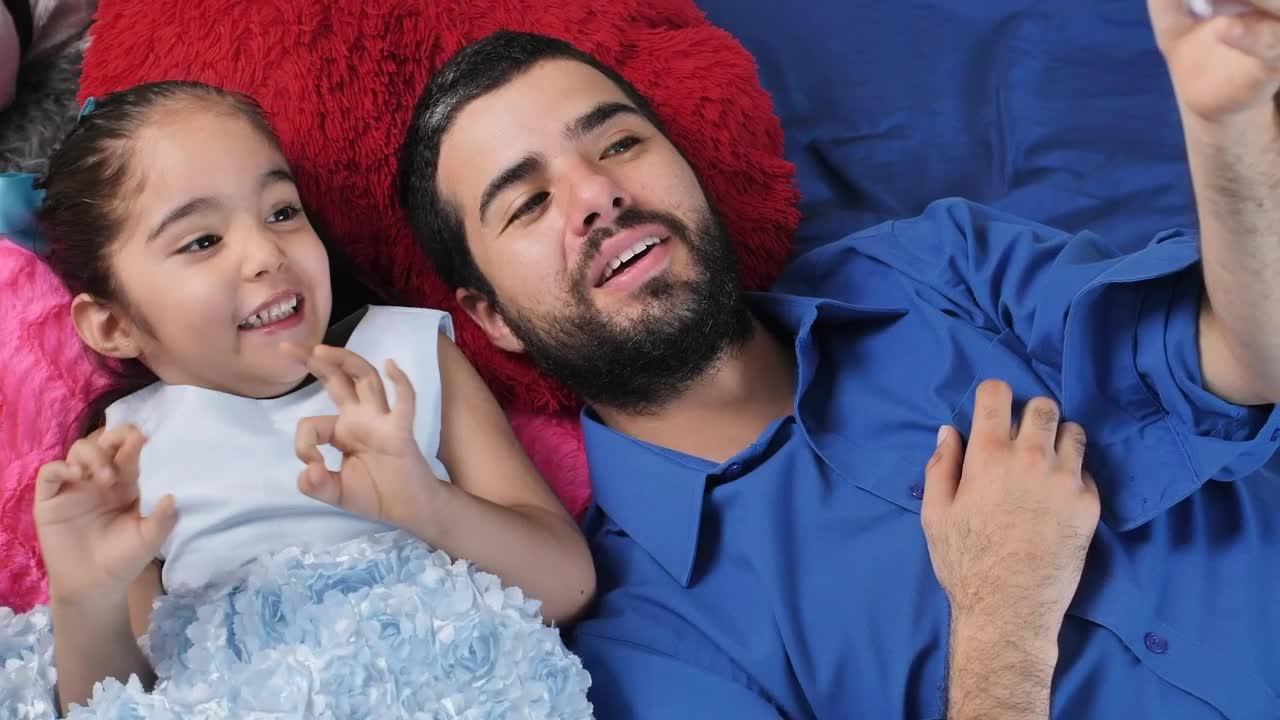 Stock Video Dad And Daughter Lying Excitedly Watching A Video On A Live Wallpaper For PC - Free Download