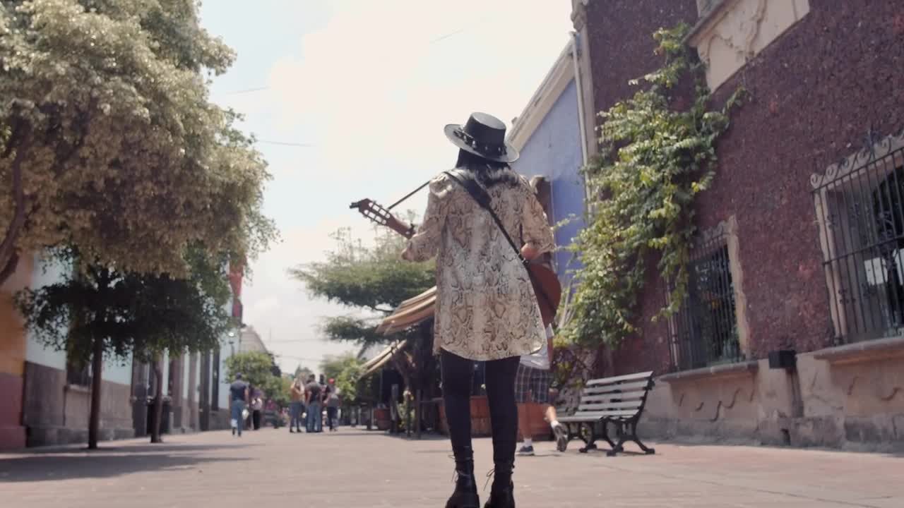 Stock Video Mujer Caminando Por Una Calle Colonial Mientras Toca Su Guitarra Live Wallpaper - Free Download
