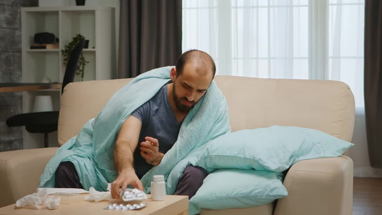Video Stock Quarantined Sick Man Sits On Sofa Holding Medication Live Wallpaper Free - Free Download