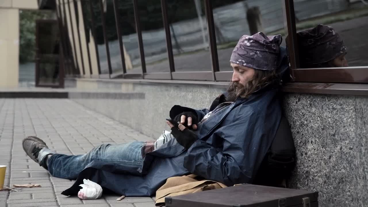 Stock Video Homeless Man Checking The Mobile Phone On The Sidewalk Animated Wallpaper - Free Download