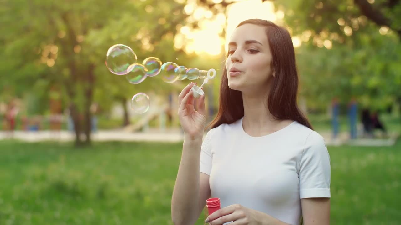 Video Stock Cheerful Girl Blowing Soap Bubbles In A Park Live Wallpaper For PC - Free Download