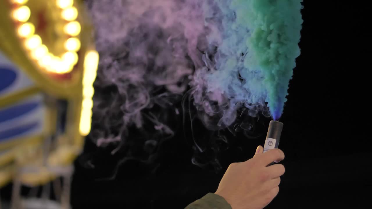 Stock Video Hand Holding A Multicolored Smoke Bomb At The Fair Live Wallpaper For PC - Free Download