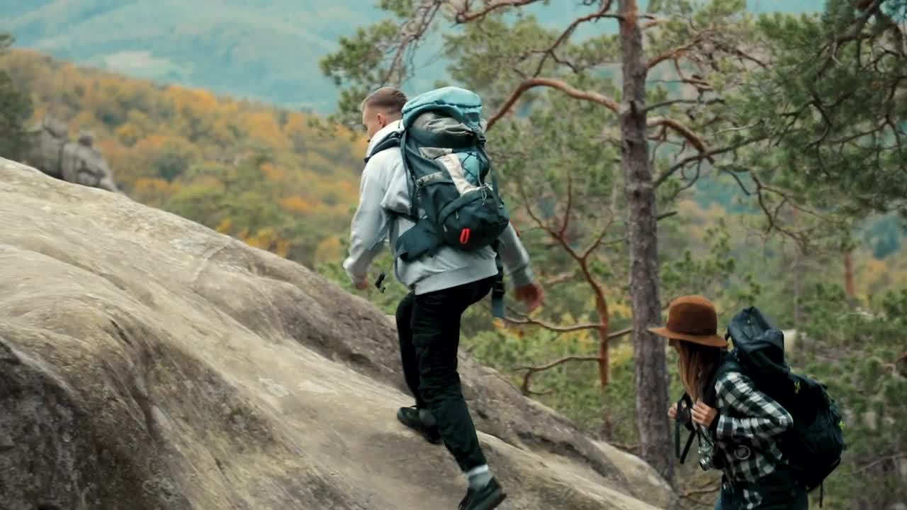 Stock Video Man Helps Girlfriend Climb Up Rock During Hike Animated Wallpaper - Free Download