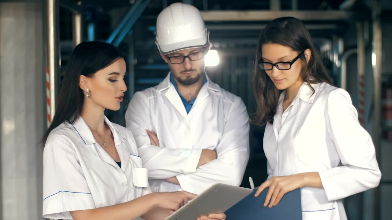 Video Stock Quality Inspectors Reviewing Reports On A Tablet Live Wallpaper Free - Free Download