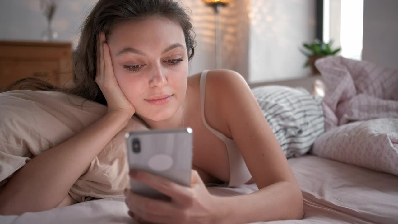 Free Stock Video Relaxed Woman On Bed Looking At Her Smartphone Live Wallpaper - Free Download