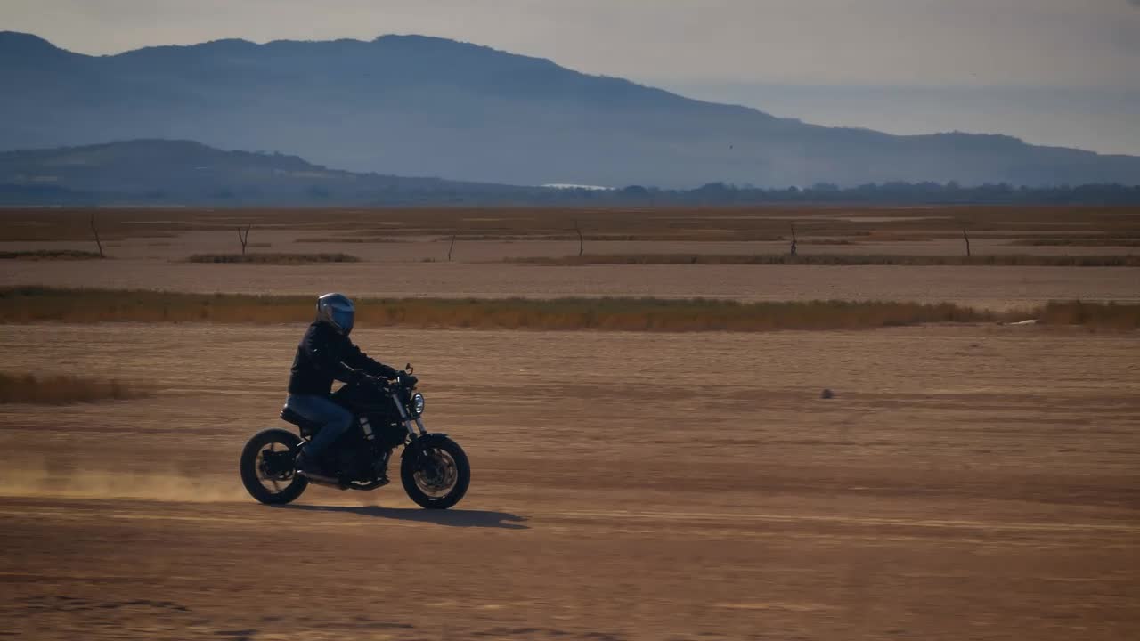 Stock Video Motorcyclist Crossing A Desert Surrounded By Mountains Live Wallpaper - Free Download