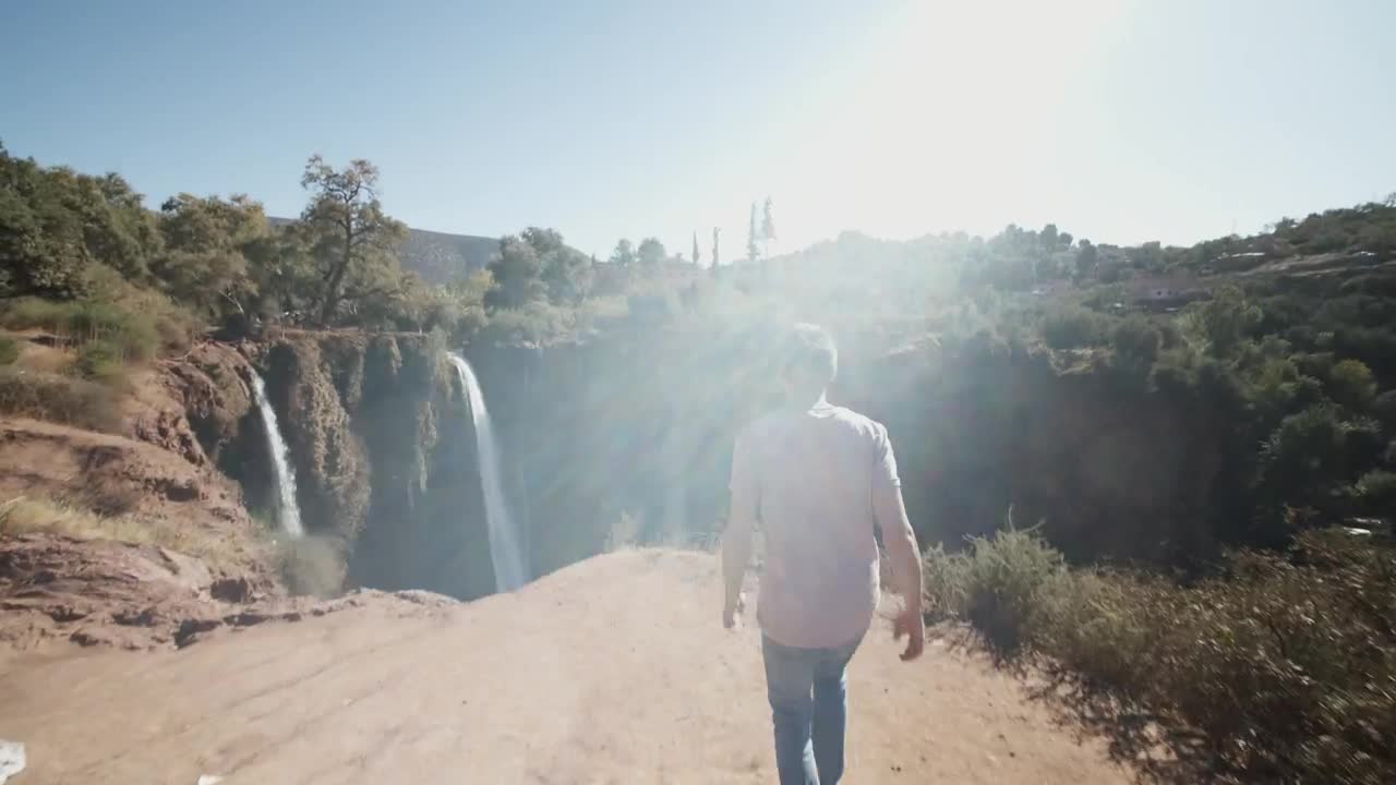 Stock Video Man Walks To A Deep Canyon With Waterfall Animated Wallpaper - Free Download
