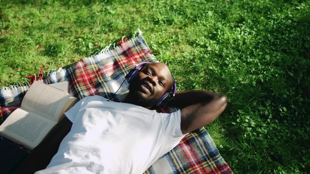 Stock Video Man Sings Along To Music Lying In Park With Headphone Animated Wallpaper - Free Download