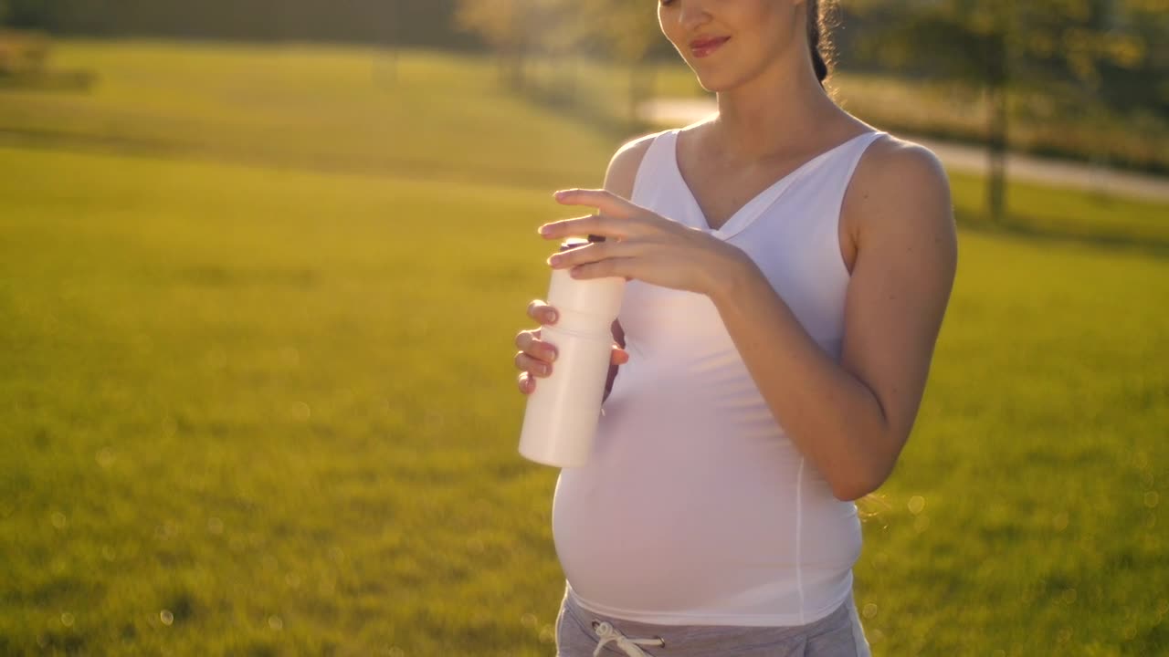 Video Stock Pregnant Woman Drinks Water On Her Walk In The Park Live Wallpaper Free - Free Download