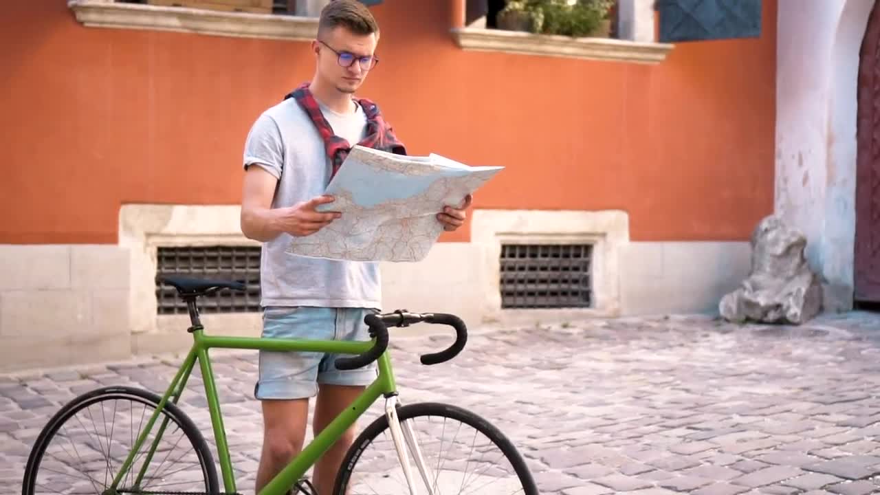 Free Video Stock tourist on bicycle checks map in european town Live Wallpaper - Free Download