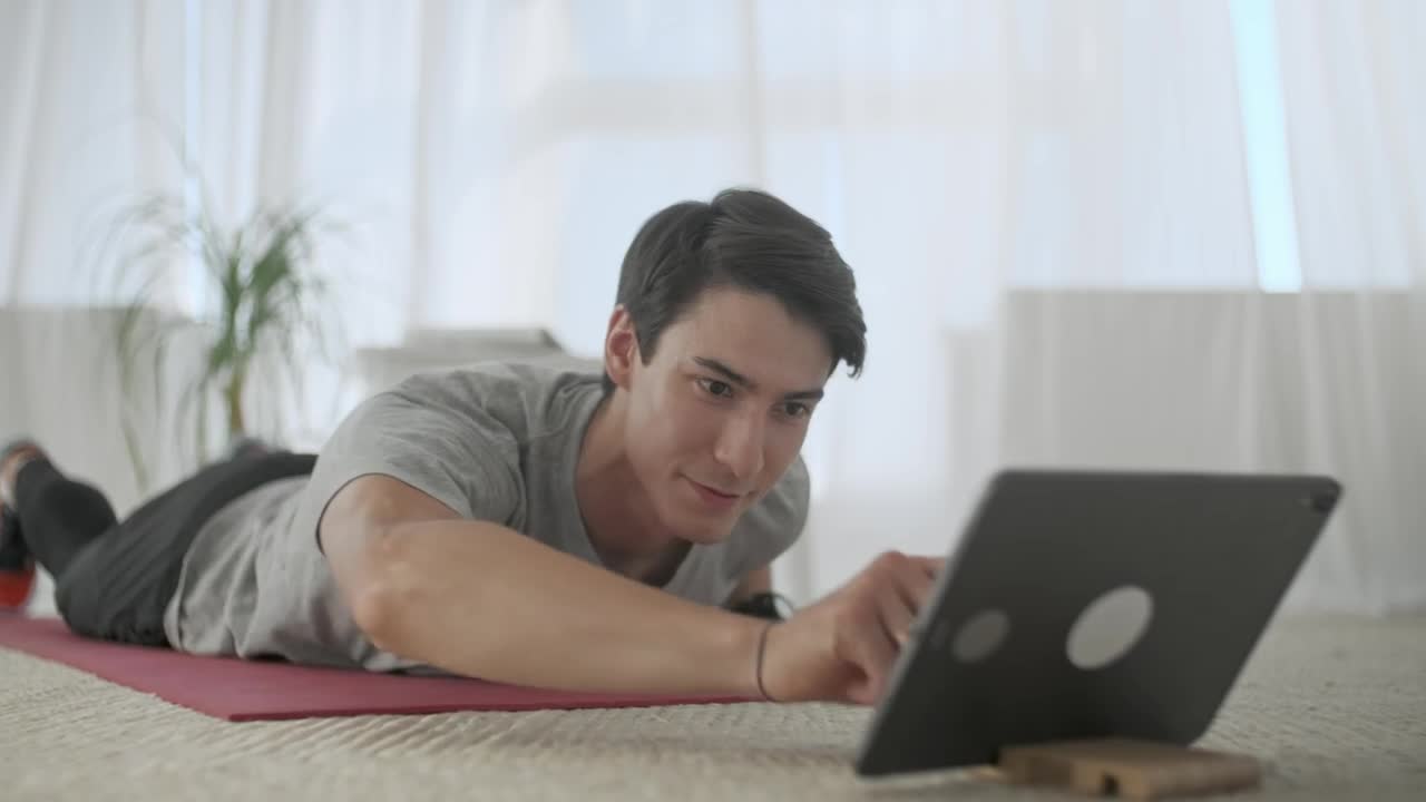 Stock Video Man Watching Exercises On A Tablet To Practice The Animated Wallpaper - Free Download